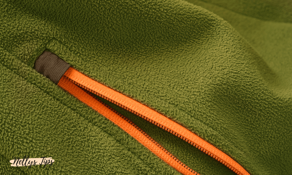 Detaljbild av grön fleece med orange dragkedja – exempel på material i softshellplagg för dam.