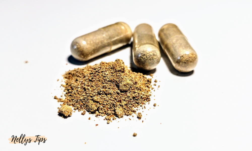 Öppnade kapslar med ashwagandhapulver utspritt bredvid fyllda kapslar