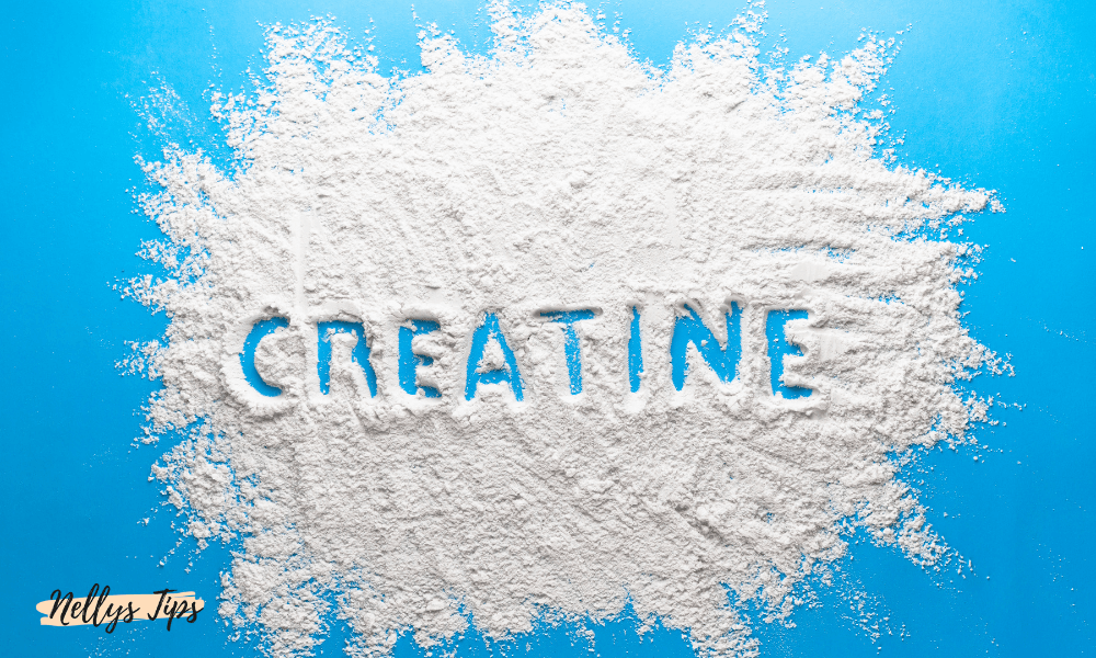 Kreatinpulver utspritt i hög med texten creatine formad i pulvret för kosttillskott.